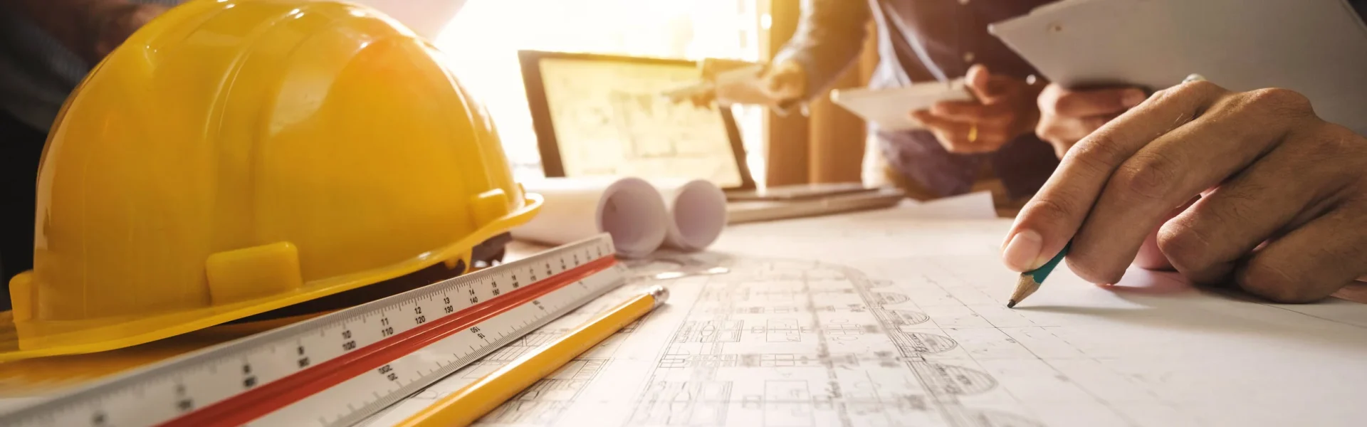 Yellow hard hat and floor plans on a desk during a construction project review